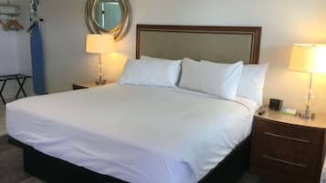 A neatly made bed with white linens, a wooden headboard, two bedside tables with lamps, and a mirror on the wall.
