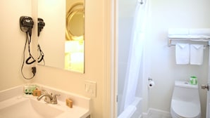 A bathroom with a sink, mirror, hair dryer, and toilet. - Travelodge by Wyndham Crescent City (Crescent City)