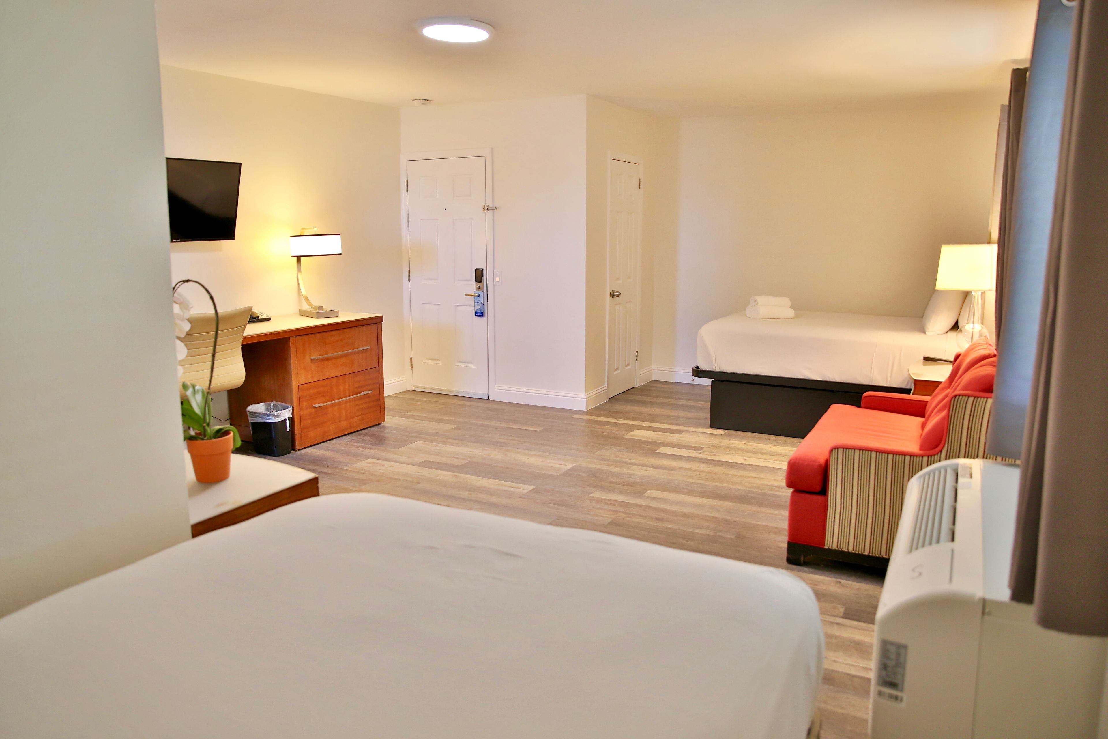 Quarto de hotel com uma cama, uma escrivaninha, uma cadeira, um armário e uma televisão.