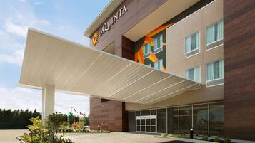A modern hotel with a prominent 'La Quinta' sign, a covered entrance, and a landscaped outdoor area.