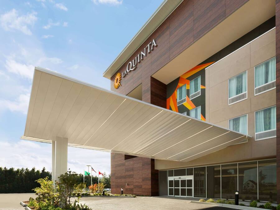 A modern hotel with a prominent 'La Quinta' sign, a covered entrance, and a landscaped outdoor area.