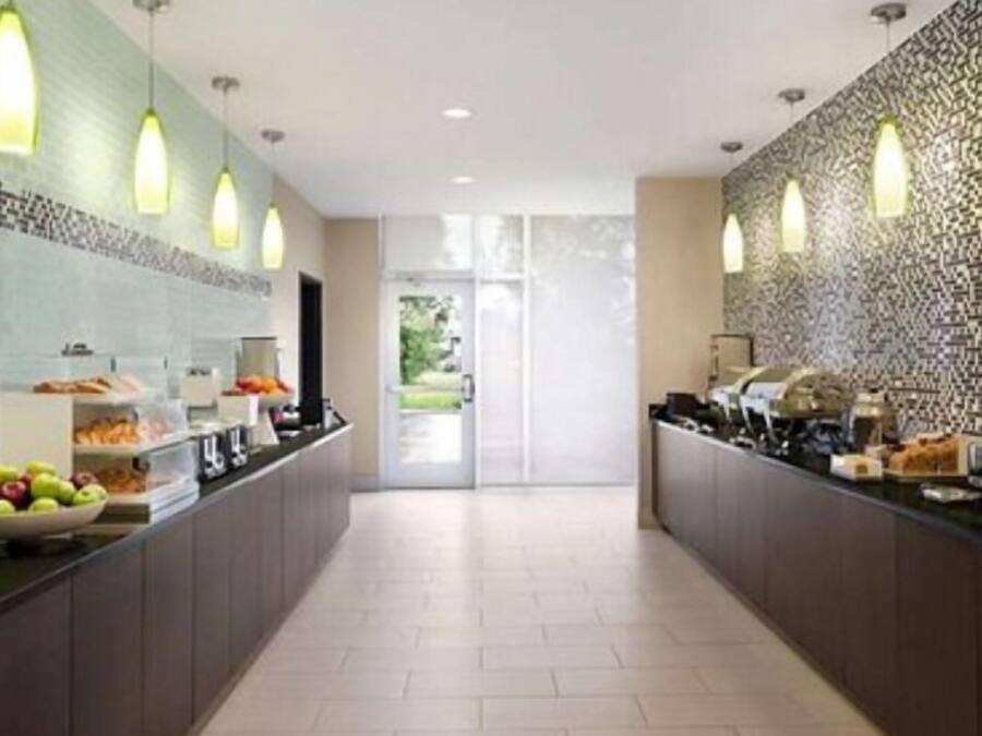 A modern kitchen with a long counter, overhead lighting, and a patterned backsplash.