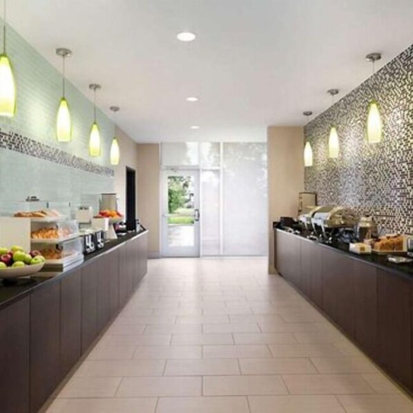 A modern kitchen with a long counter, overhead lighting, and a patterned backsplash. - La Quinta Inn & Suites by Wyndham Burlington (Burlington)