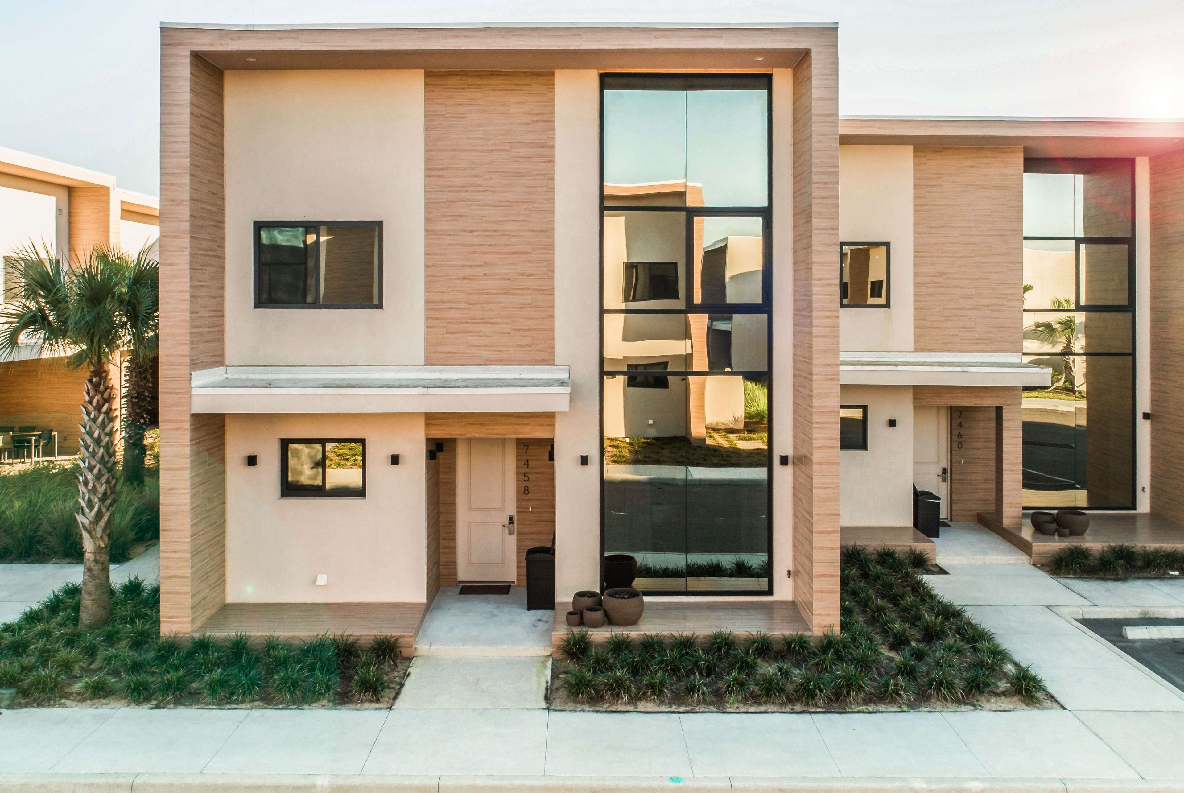 A modern multi-story residential building with a minimalist design, featuring large windows and a flat roof.