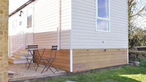 En etplans campingvogn med veranda, et bord og to stole.