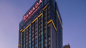 Ein hoch aufragendes Hotel mit einem gut sichtbaren Schild, auf dem "RAMADA BY WINDHAM" steht.