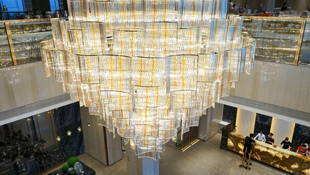 Ein modernes Interieur mit einer großen, aufwendigen Chandelier, einer Rezeption und einem Marmorboden.