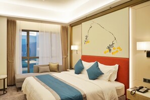 Une chambre d’hôtel avec un lit, une table de chevet avec un téléphone, une fenêtre avec des rideaux et un mur orné d’un tableau.