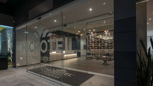 A modern hotel entrance with glass doors, a reception desk, and a patterned interior visible through the glass. - Microtel Inn & Suites by Wyndham Irapuato (Irapuato)