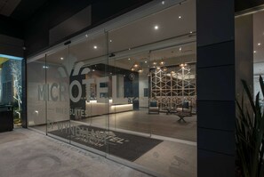 A modern hotel entrance with glass doors, a reception desk, and a patterned interior visible through the glass. - Microtel Inn & Suites by Wyndham Irapuato (Irapuato)