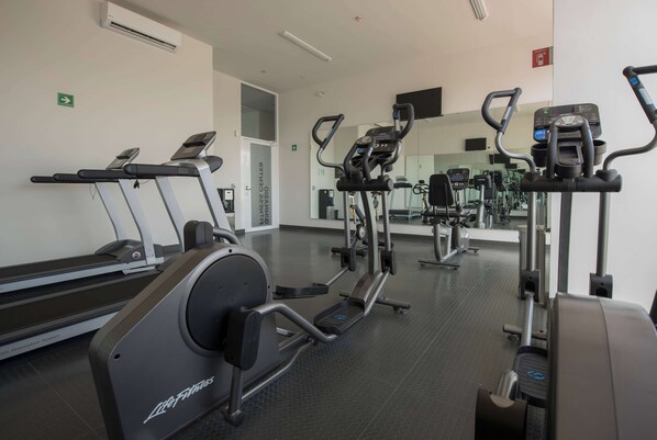 Uma academia com esteiras, elípticos e equipamentos de musculação.