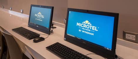 Dos monitores de computadora sobre un escritorio con teclados y ratones, mostrando el logotipo de Microtel Inn & Suites by Wyndham.