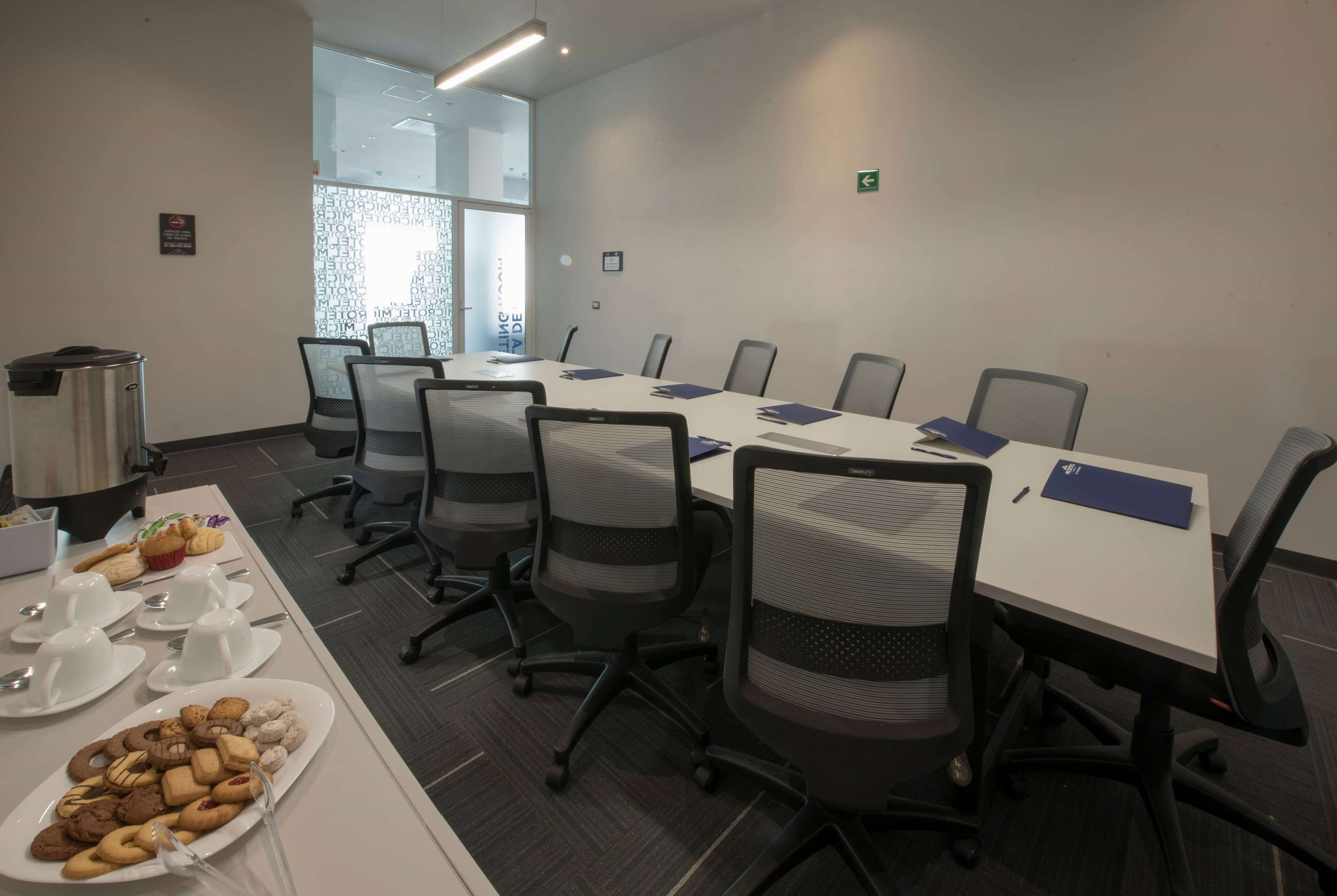 A conference room with a long table, chairs, and a buffet table with food and drinks.
