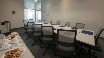A conference room with a long table, chairs, and a buffet table with food and drinks.