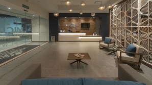 A modern hotel lobby with a reception desk, seating area, and decorative wall panels. - Microtel Inn & Suites by Wyndham Irapuato (Irapuato)