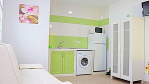 A compact room with a sofa, a washing machine, a microwave, and a cabinet. - Very central apartment with WiFi (CONIL DE LA FRONTERA)