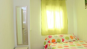 A bedroom with a bed, a nightstand, a mirror, and a window with curtains. - Very central apartment with WiFi (CONIL DE LA FRONTERA)
