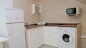 A compact kitchen with a washing machine, a microwave, and a refrigerator. - Central one bedroom apartment with WiFi (CONIL DE LA FRONTERA)