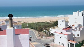 A coastal town with a beach, white buildings, and a road leading to the beach. - Great location close to the beach (CONIL DE LA FRONTERA)