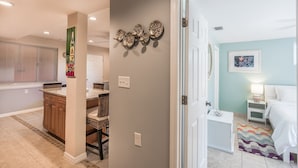 Una cocina con comedor, una puerta blanca que da a un dormitorio y un baño con ducha.