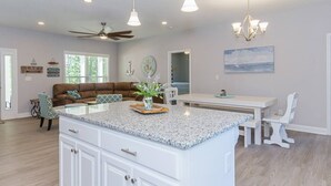A spacious kitchen with a central island, a dining area, and a living room with a sofa.