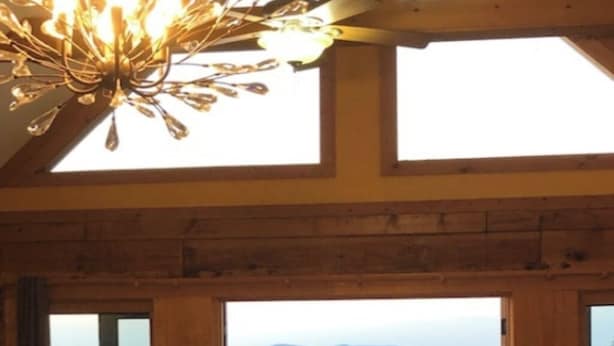 A wooden interior with a large window and balcony overlooking a mountainous landscape. - Cozy mountain log chalet overlooking the slopes of Hatley Pointe Ski Resort.  (Mars Hill)