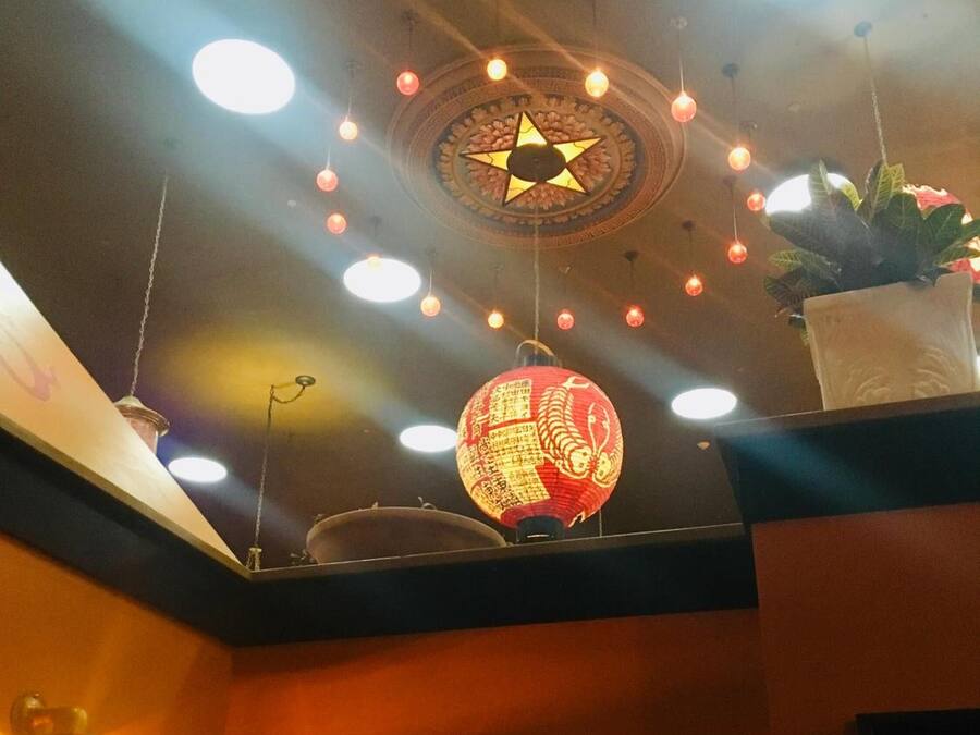Un plafond orné de motifs en forme d’étoiles, des luminaires suspendus, une lanterne rouge et une plante en pot.