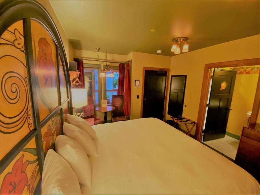 Ein Hotelzimmer mit einem großen Bett, einem Schreibtisch mit Stuhl, einem kleinen Tisch und einem Spiegel.