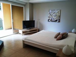 A modern bedroom with a bed, a television, and a wall art piece.