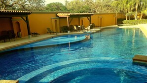 Une piscine à l’eau d’un bleu cristallin, entourée de chaises longues et d’un espace de repos abrité.