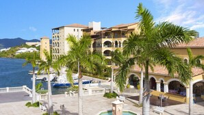 A waterfront hotel with a central courtyard, palm trees, and a fountain. - Agua Azul by Island Properties Online (Lowlands)