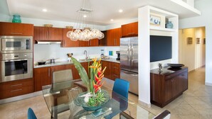 A modern kitchen with stainless steel appliances, wooden cabinets, and a glass dining table with chairs. - Agua Azul by Island Properties Online (Lowlands)
