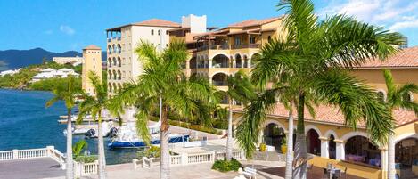 A resort with a pool, palm trees, and a view of the sea.