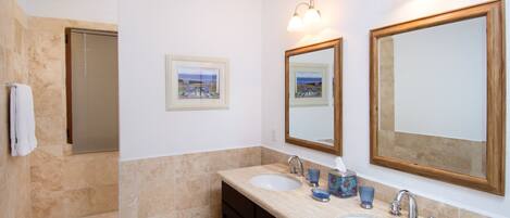 A bathroom with two sinks, a mirror, and a towel rack.