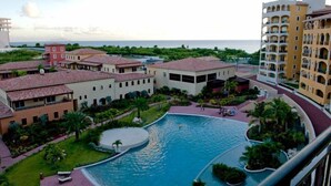 A resort with a central pool, multiple buildings, and a view of the ocean. - Artimino by Island Properties Online (Lowlands)