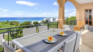 A balcony with a table set for two, overlooking a coastal view. - Artimino by Island Properties Online (Lowlands)