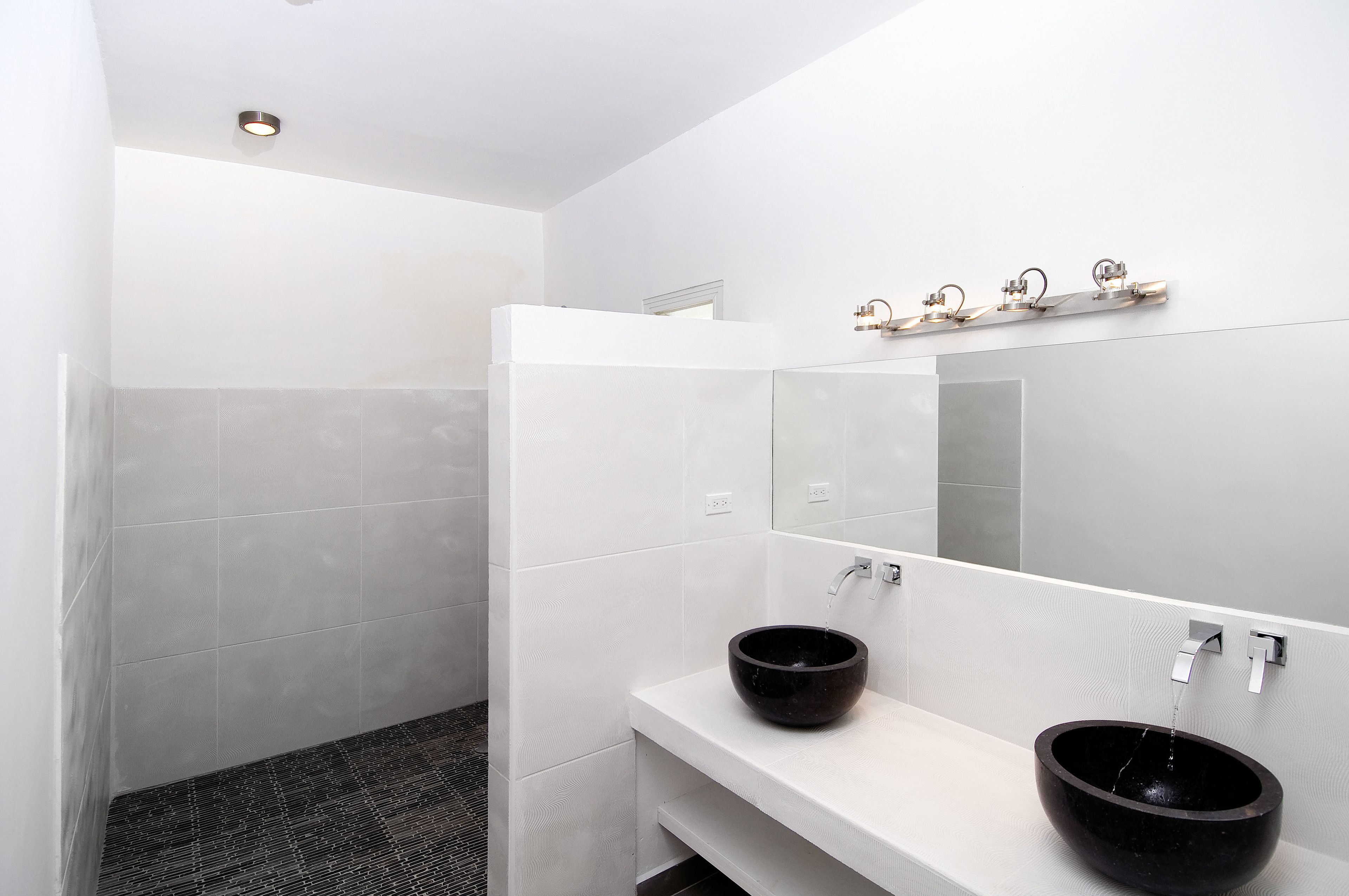 Un baño moderno con dos lavamanos, un espejo grande y una zona de ducha.
