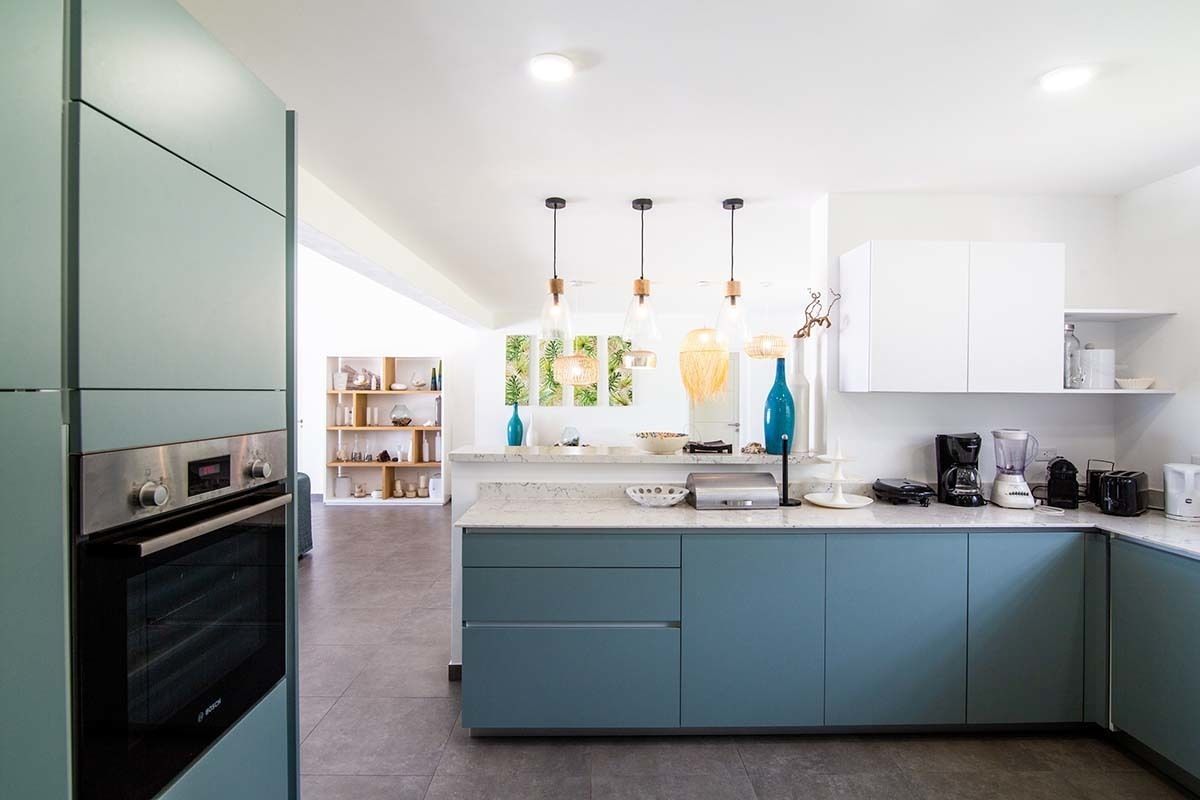 A modern kitchen with a built-in oven, a central island with a sink, and pendant lighting.