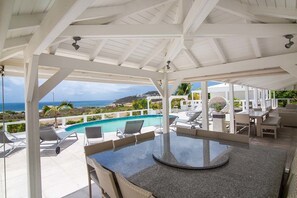 A covered outdoor area with a pool, lounge chairs, and a table. - Alizee by Island Properties Online (Philipsburg)