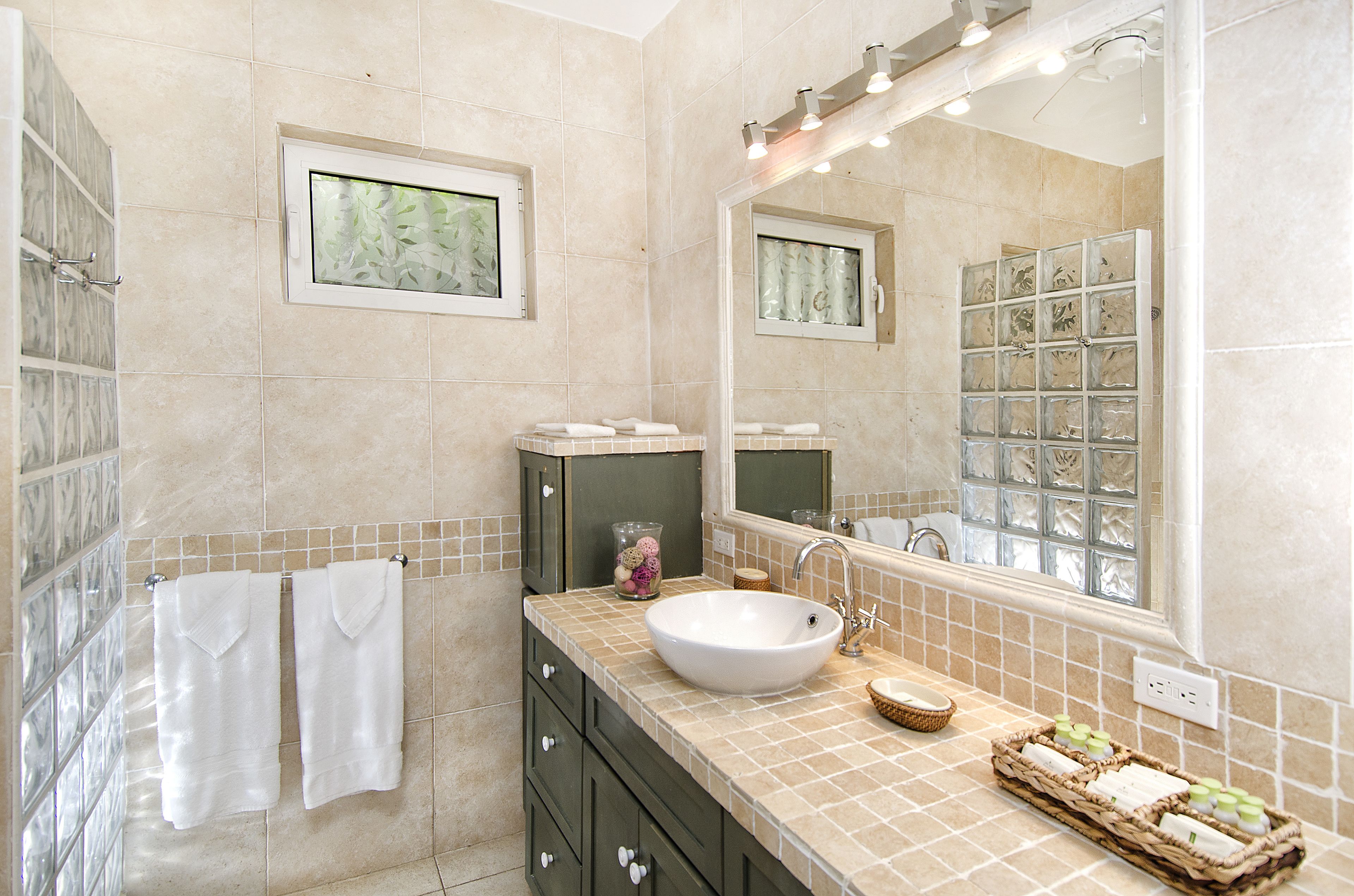 A bathroom with a large mirror, a sink, and a tiled floor.