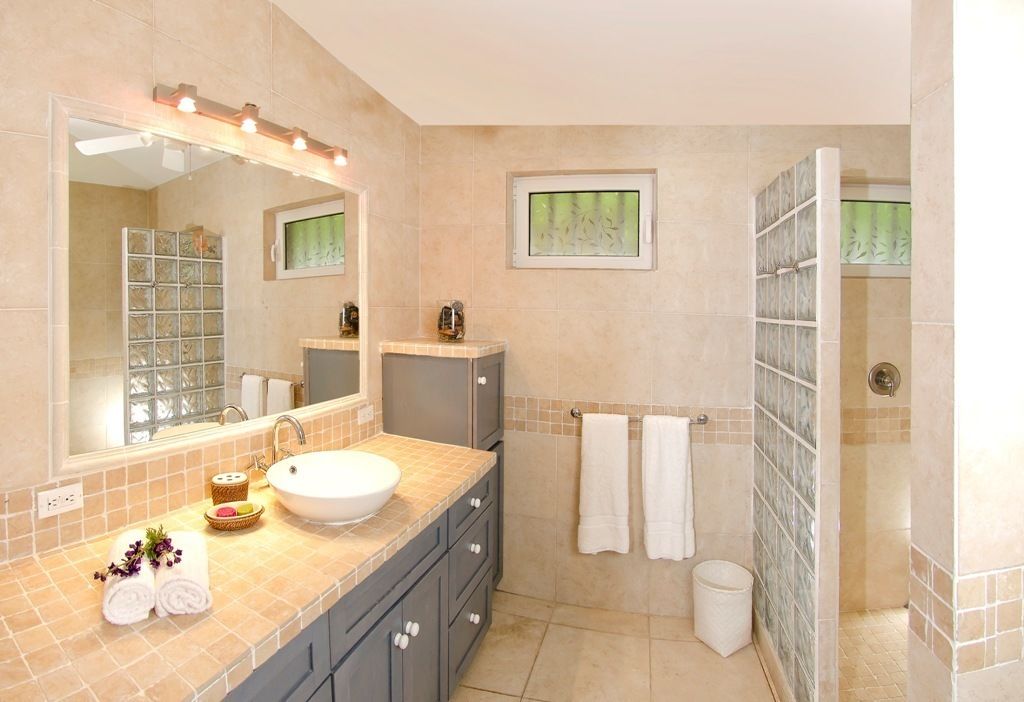 A bathroom with a large mirror, a sink, a shower, and a toilet.