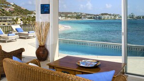 A balcony with wicker furniture, a vase, and a table with a decorative plate. - Beach House Younes by Island Properties Online (Oyster Pond)