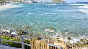 A wooden deck leading to the sea with a sign indicating stairs to the sea. - Beach House Younes by Island Properties Online (Oyster Pond)