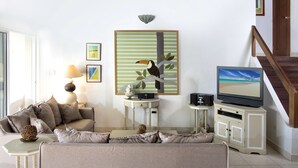 Un salon avec un canapé, un téléviseur, une lampe et un tableau au mur.