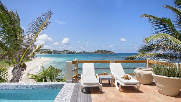 Un espace piscine avec des chaises longues et vue sur la plage.