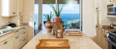 A kitchen with a large island, cabinets, and a view of the ocean.