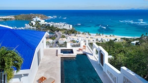 Um resort com piscina com vista para o oceano, estrada que leva à praia e panorama da costa.