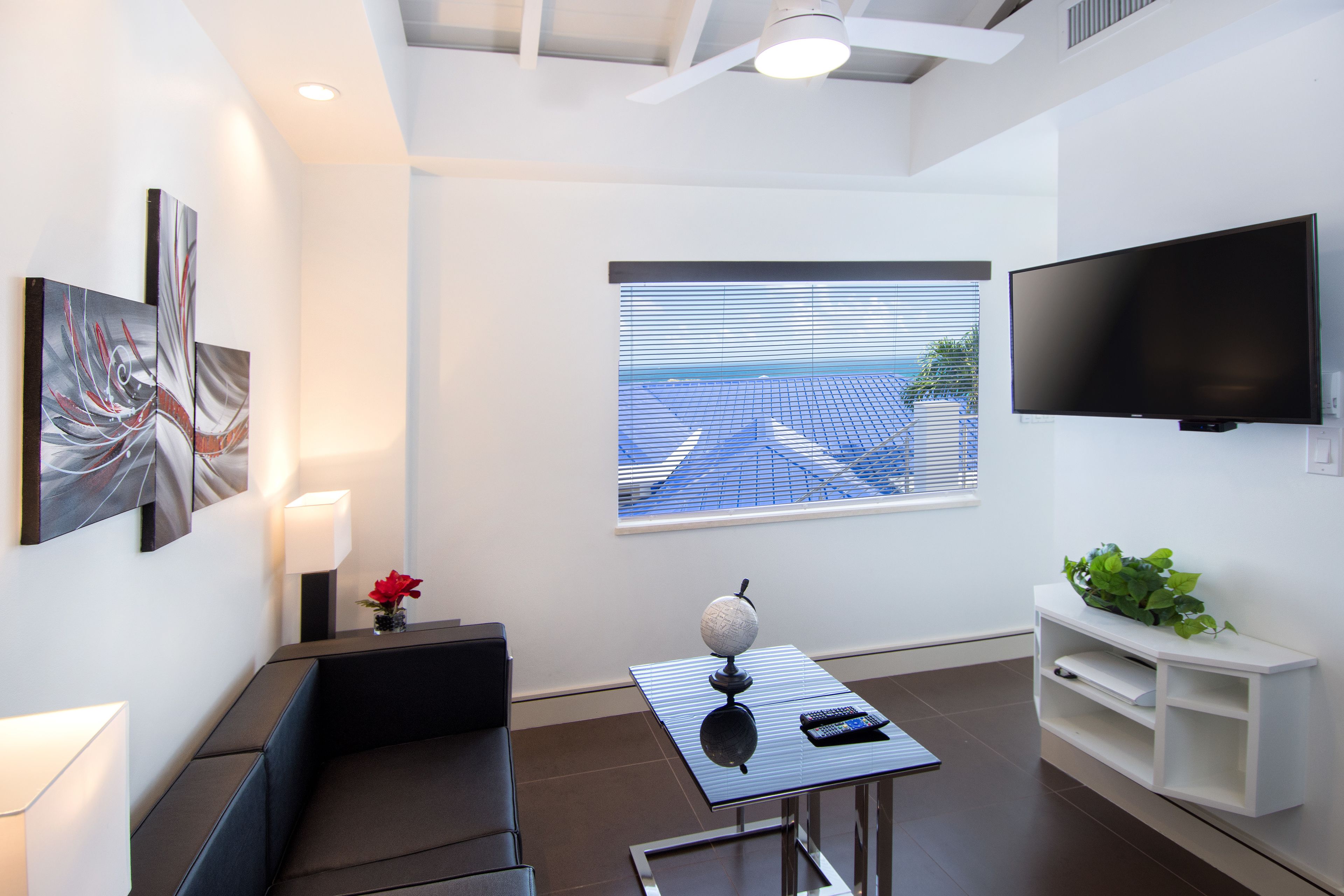 Una sala de estar moderna con un sofá, una mesa de centro con un globo terráqueo, un televisor y una ventana con persianas.