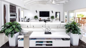 Uma sala de estar moderna com um sofá branco, uma mesa de centro e duas plantas em vasos.