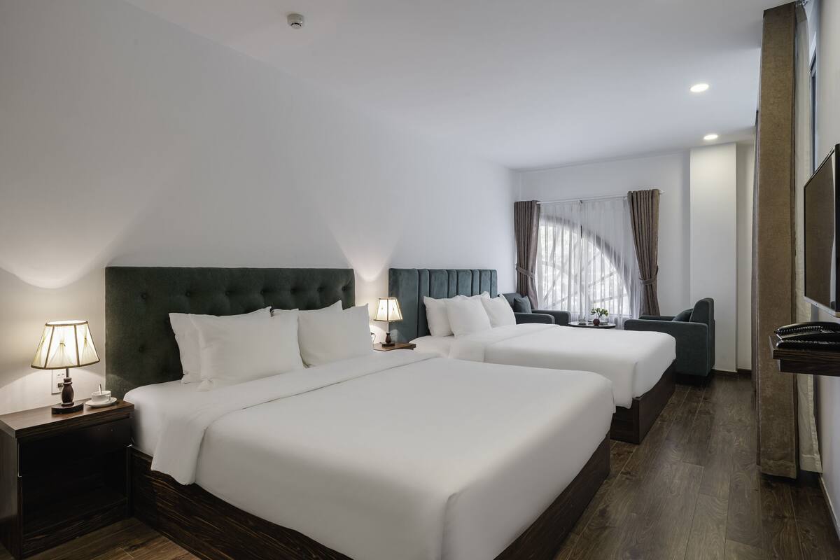 Una habitación de hotel con dos camas, un sofá, un televisor y una lámpara.